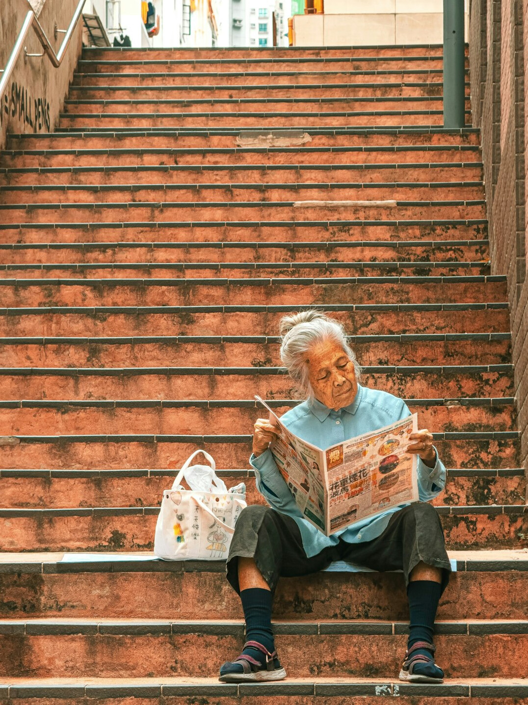 Elderly Japanese man reading a newspaper at home by the window